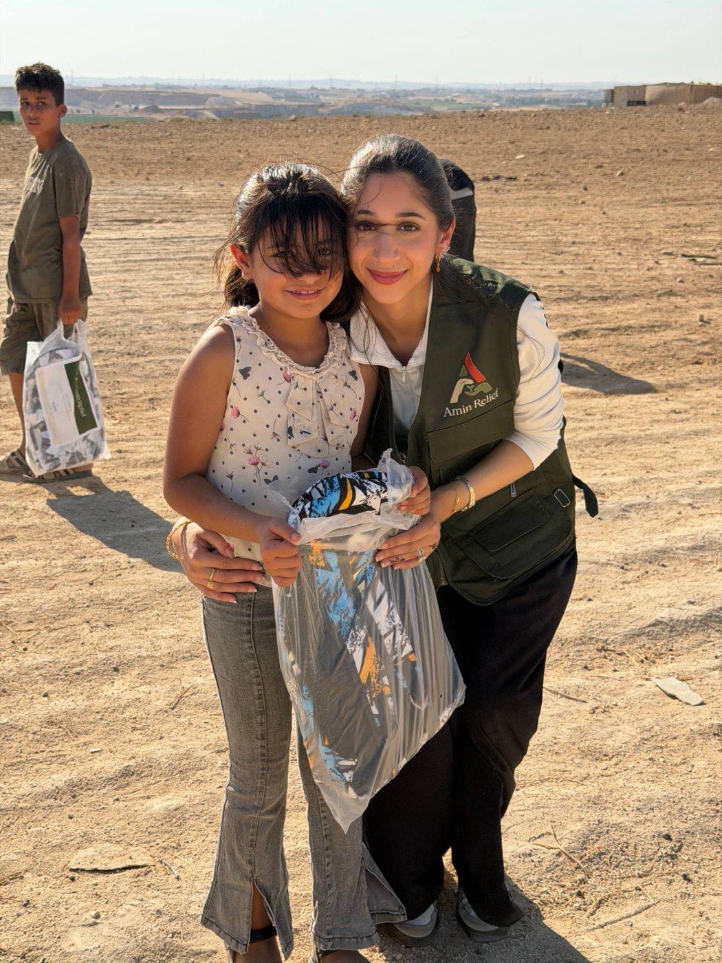 An Amin Relief volunteer with a girl holding the kit she has just been given
