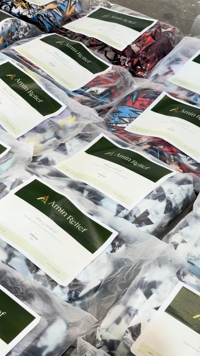 Back-to-school kits bagged and laid out, each under an Amin Relief card naming the donor