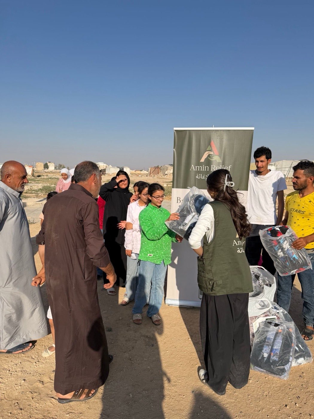 An Amin Relief volunteer handing a wrapped package to a girl at the distribution