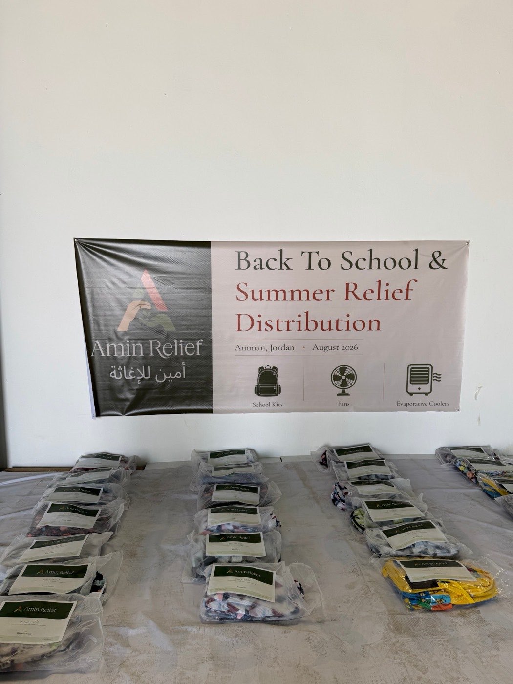 Stickered packages laid out in rows beneath the Amin Relief distribution banner